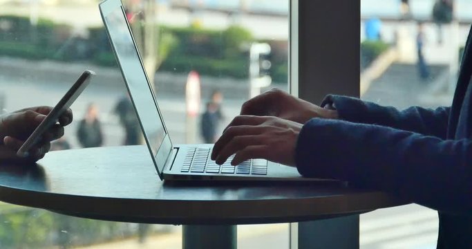 4k silhouette of people working on laptop computer in coffee shop desk,using smartphone,city pedestrian and traffic window view,keyboard input,write article,writing report.