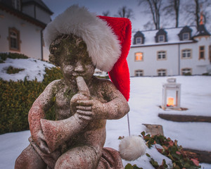 Little angel with horn in santa hat in romantic winter scene outside. Merry Christmas holiday!