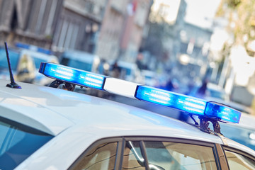 Police car with blue lights on the crime scene in traffic / urban environment.