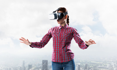 Girl in checked shirt wearing VR glasses experiencing another re