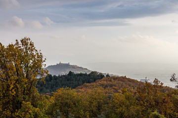 Beautiful view of Assisi town (Umbria) in autumn from an unusual place, behind an hill with orange,...