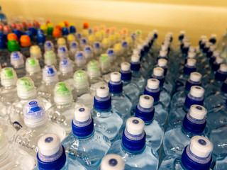 Plastic bottles with mineral water. Closeup on water bottles in raw and lines. Plastic bottles, colorful caps. Plastic bottles with water, lids. 