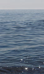 Close up of sparkling surface of sea with waves and sky background
