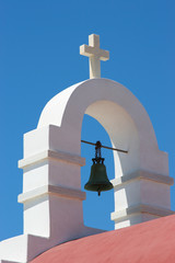 White Cross and Church Steeple in front of a blue sky on the island of Mykonos, Greece