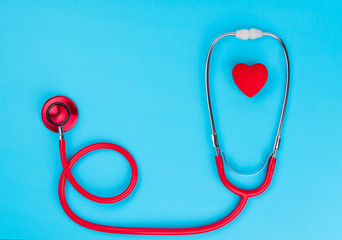 Red heart and stethoscope on on blue background.
