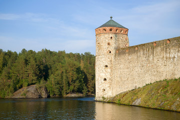 Fototapeta na wymiar The tower of the medieval fortress Olavinlinna close up against the backdrop of the coast. Savonlinna, Finland