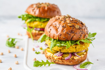 Vegan chickpeas burgers with arugula, pickled cucumbers and hummus.