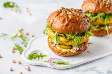 Vegan chickpeas burgers with arugula, pickled cucumbers and hummus.