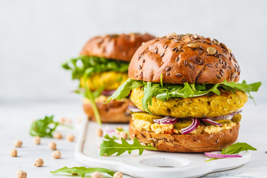 Vegan chickpeas burgers with arugula, pickled cucumbers and hummus, copy space.