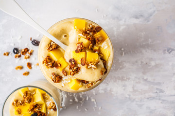 Mango banana smoothie with granola and coconut in a jar, top view.