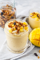 Mango smoothie with granola and coconut in a jar.