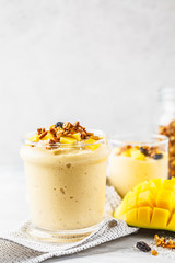 Mango smoothie with granola and coconut in a jar.