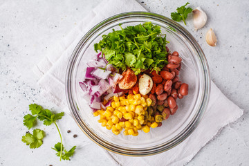 Ingredients for vegan meatballs from beans and corn in glass bowl.