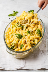 Casserole with pasta, chicken, broccoli and cheese crust in a glass form.