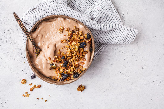 Chocolate smoothie bowl with granola in a coconut bowl, copy space.