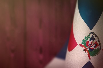 Dominican Republic flag for honour of veterans day or memorial day. Glory to the Dominican Republic heroes of war concept on pink blurred natural wood wall background.