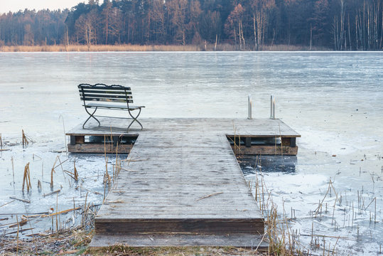 Einsamer Steg am zugefrorenem See im Winter