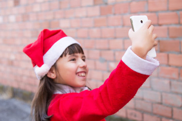 Obraz na płótnie Canvas girl dressed as santa claus making a selfie with the mobile phone
