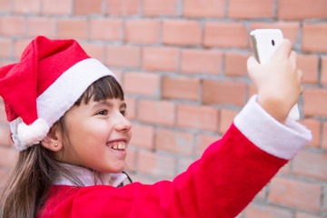girl dressed as santa claus making a selfie with the mobile phone