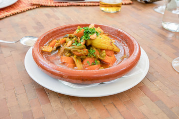 delicious tagine food, typical Maghrebi and North African dish, on a brown ceramic bowl with spoon on table