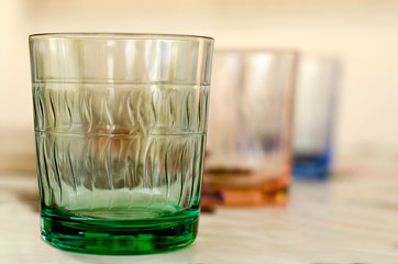 Colour water glasses in a row and blurred background.