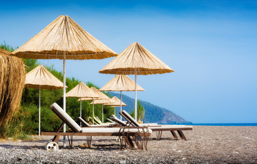 Chaise lounge under the straw umbrellas
