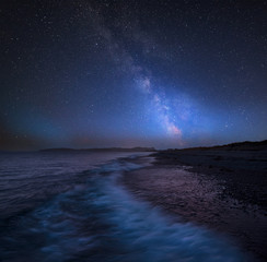 Vibrant Milky Way composite image over landscape of West coast of Wales