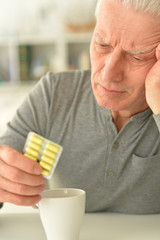 Elderly ill man with pills in hand