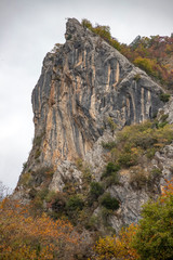 Multicolored stone cliff towering over the autumn forest. Greece