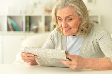 Portrait of beautiful smiling senior woman with newspaper