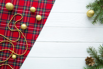Red scottish plaid on white wooden table, fir tree branches and cones. White wooden table, space...