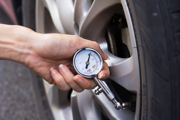 Checking car tyre pressure with gauge