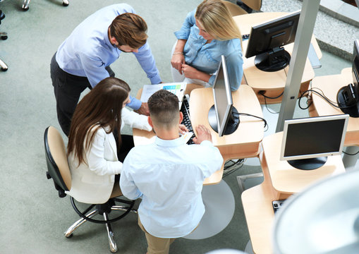 Top view of young modern colleagues in smart casual wear working together while spending time in the office.