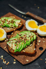 Two toasts with avocado, egg, spices and herbs