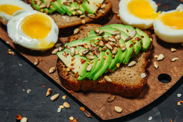 Half avocado, avocado and egg sandwiches on wooden Board