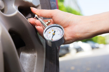 Checking car tyre pressure with gauge