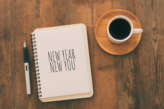 Top view of notebook and text NEW YEAR NEW YOU, cup of coffee over wooden desk.