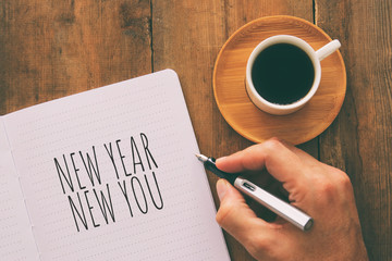 Top view of notebook and text NEW YEAR NEW YOU, cup of coffee over wooden desk.