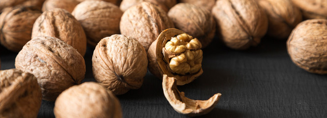Halved and whole walnuts on black background, side view. Closeup.