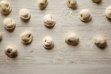 Homemade raw tortellini on white wooden surface, overhead view. Flat lay, from above.