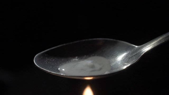 An addict prepares a dose of heroin in a spoon.