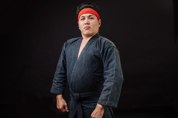 Fat confident karate fighter with serious look posing to the camera. boss in karate. strong brutal funny fighter isolated on the black background.copy space © alfa27