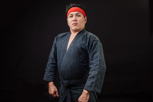 Fat confident karate fighter with serious look posing to the camera. boss in karate. strong brutal funny fighter isolated on the black background.copy space