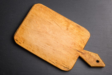 Top view of vinatge wooden cutting board on black slate stone background