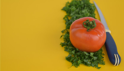 Tomato with herbs and knife.