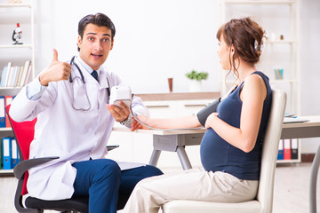 Young doctor checking pregnant woman's blood pressure