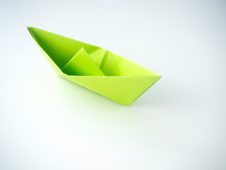 Green paper boat laid on white background..