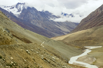 The road follow a river high in the mountains.