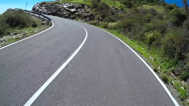 Images of a motorcycle riding a winding path in the mountains.