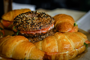 Close-up of a glass tray on a thin leg, on which are sandwiches with ham, tomatoes and greens.